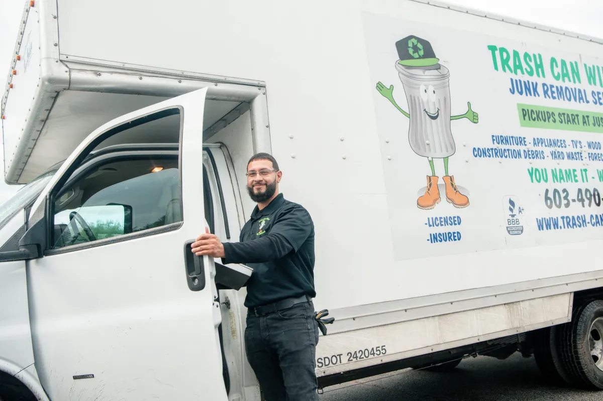 A crew member at the cab of a Trash Can Willy's box truck