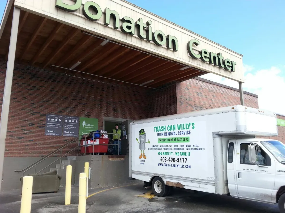 A Trash Can Willy's box truck at a donation center with bins of goods being wheeled inside