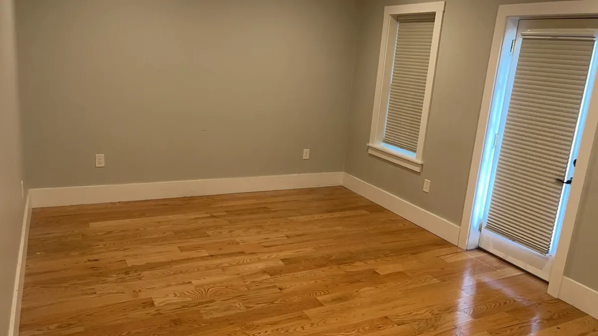 A bedroom cleared to bare floor and swept at the end of a Trash Can Willy's job
