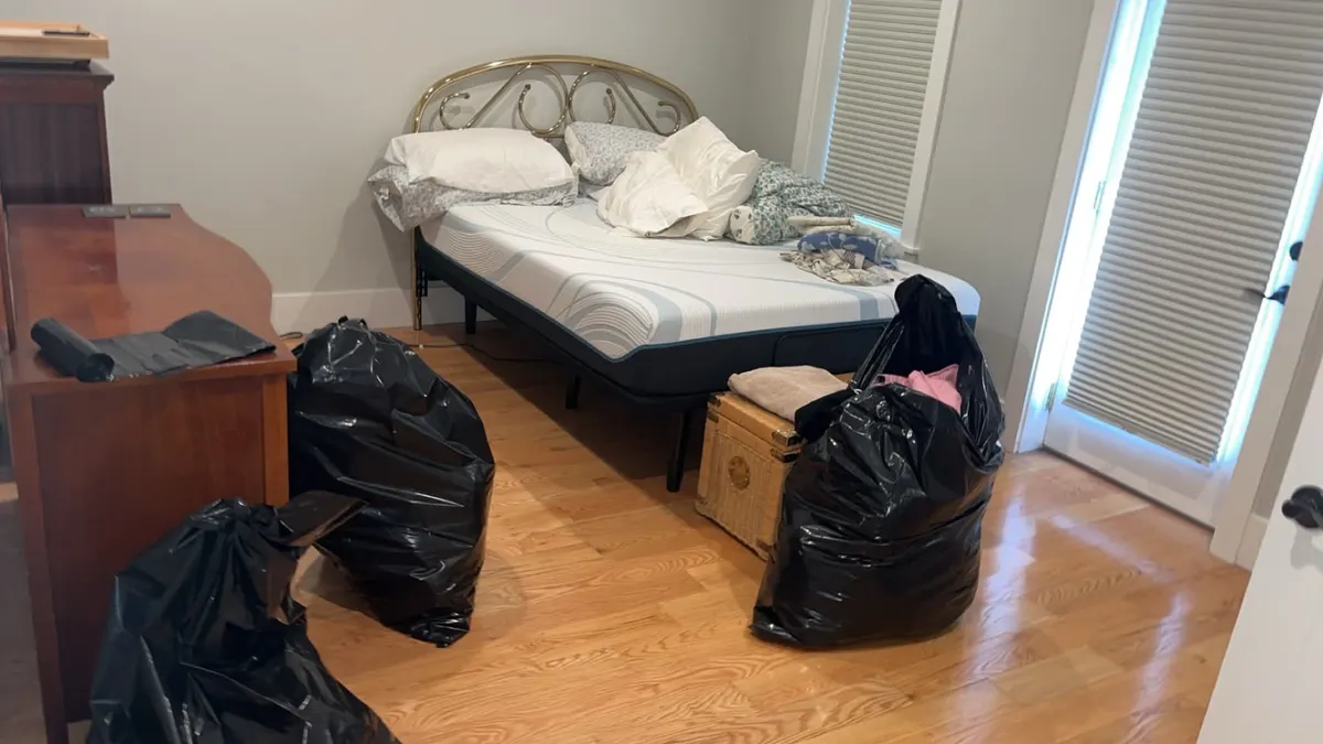 A bedroom with bagged belongings on the floor before a cleanout