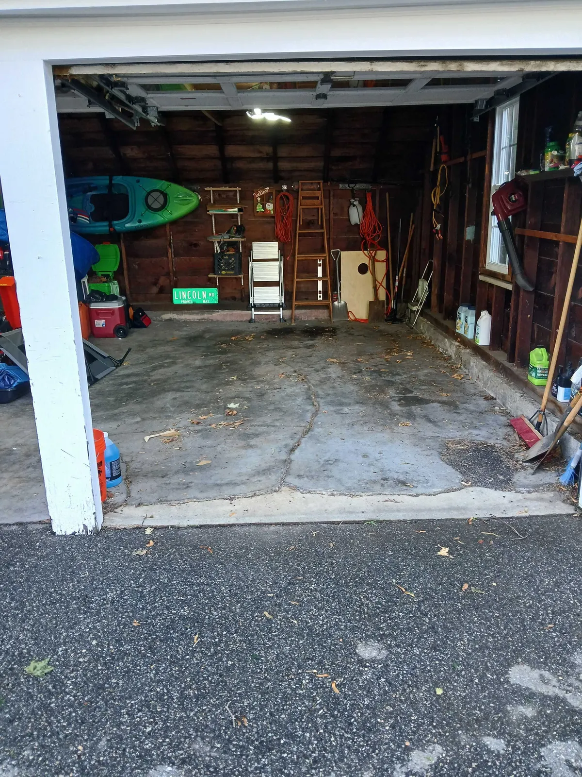 The same garage cleared back to the floor, with only the owner's kayak, step ladder and tools left