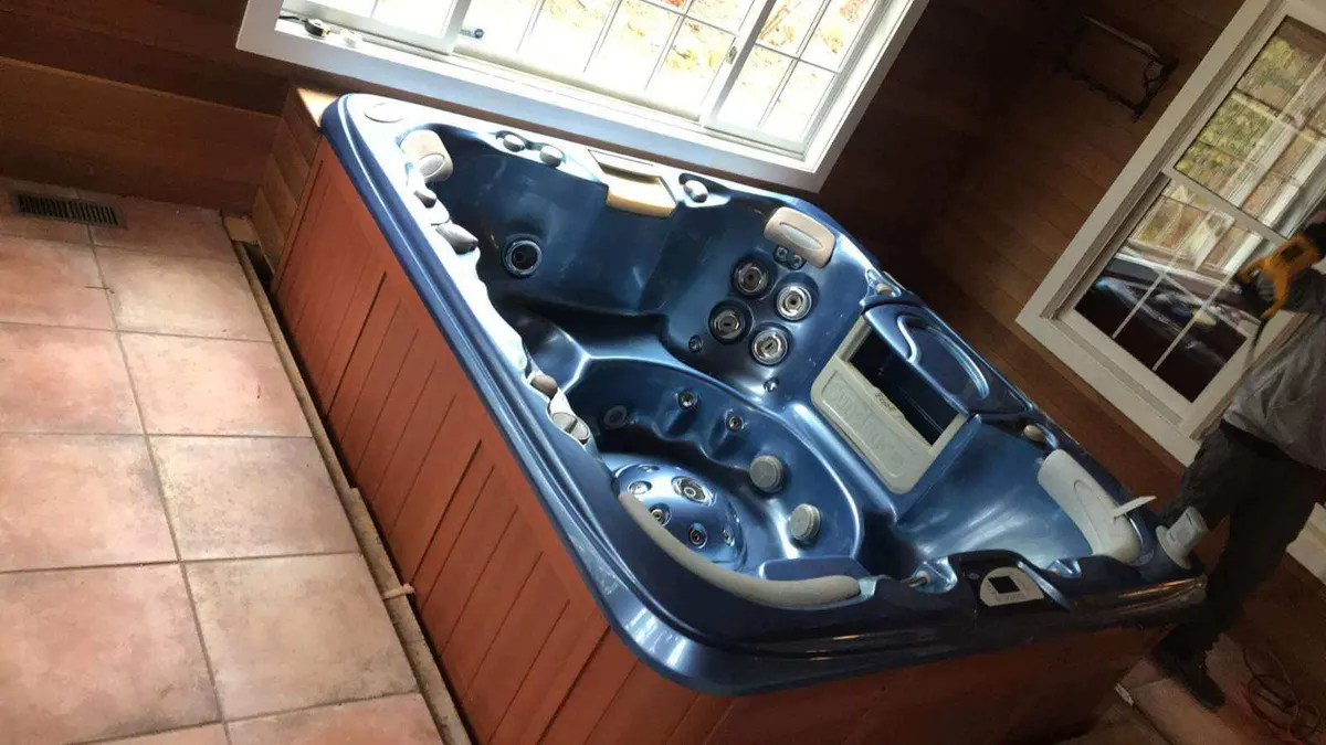A blue hot tub in a tiled sunroom before the crew cut it up and carried it out