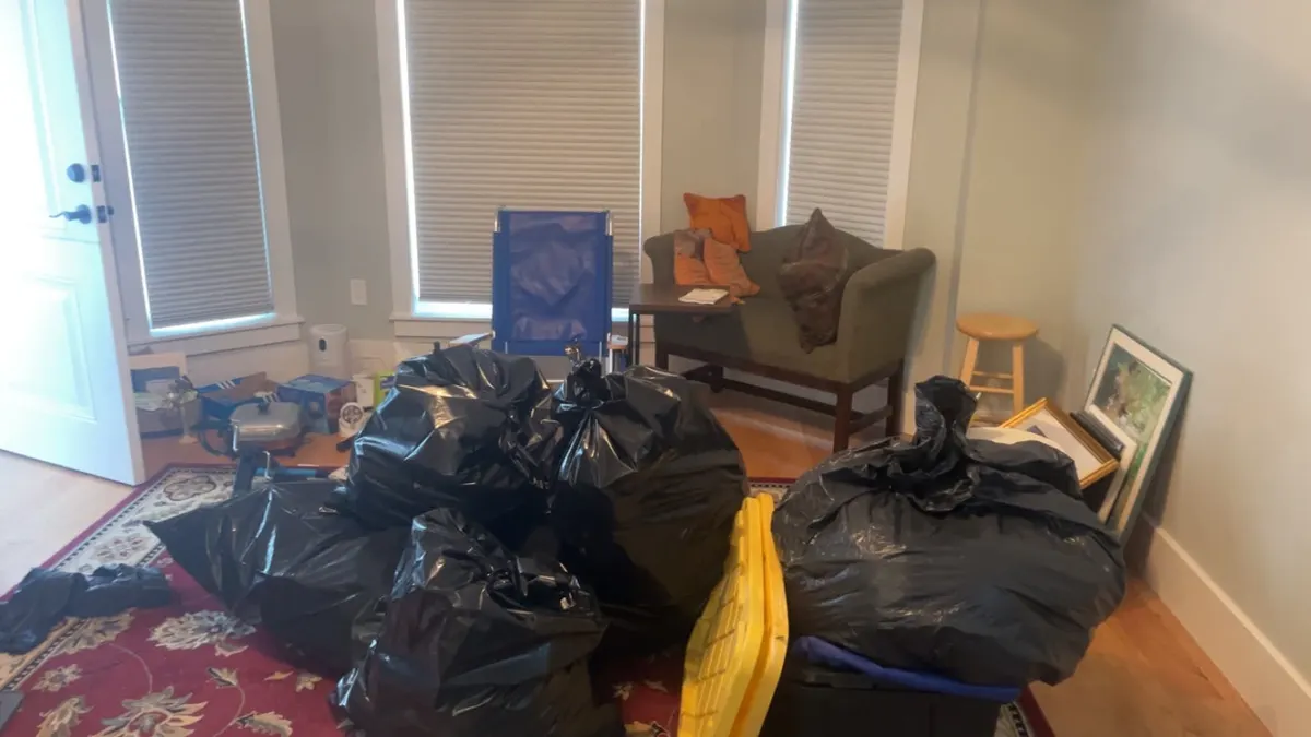 A living room with bagged belongings and a loveseat before an estate cleanout