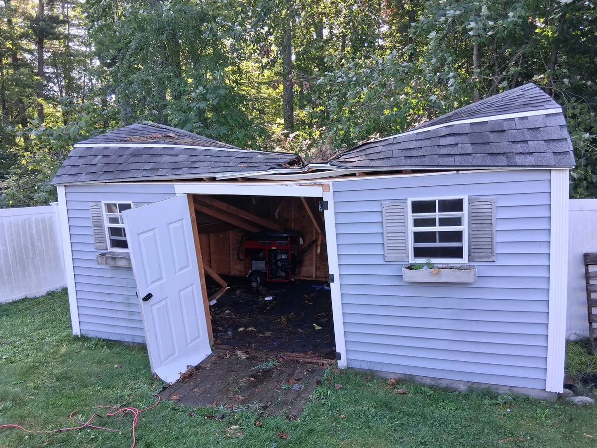 A storm damaged shed with a caved in roof, before removal