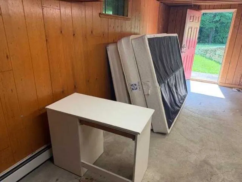 A room mid-cleanout with mattresses and furniture staged for removal